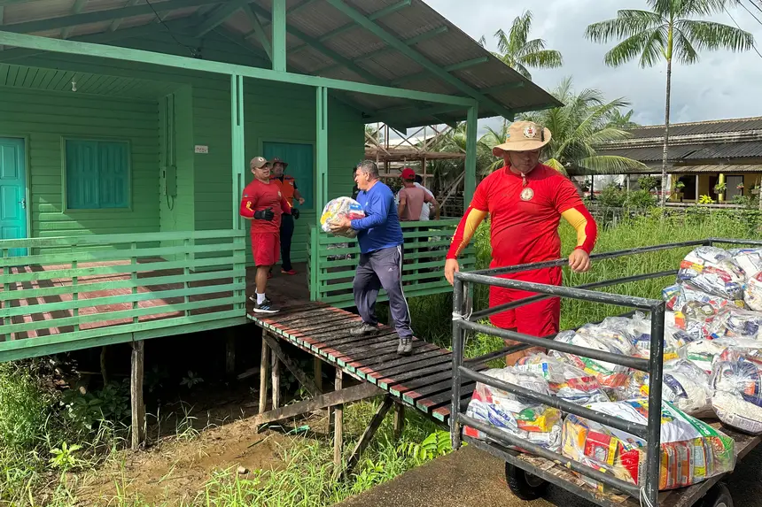 As equipes do estado realizando o transporte dos alimentos na Vila Progresso.